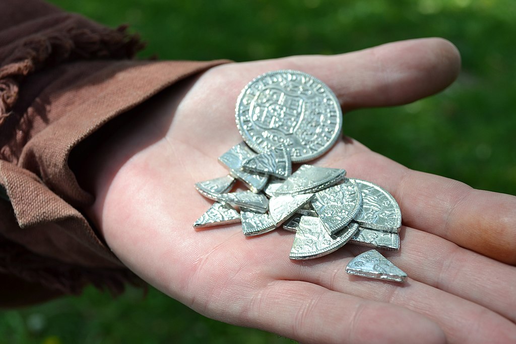 An outstretched hand holding many pieces of silver coin