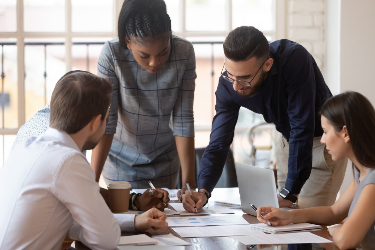 1176842719 Focused multiracial corporate business team people brainstorm on marketing plan financial report gather at office table meeting, diverse serious colleagues group discuss paperwork engaged in teamwork