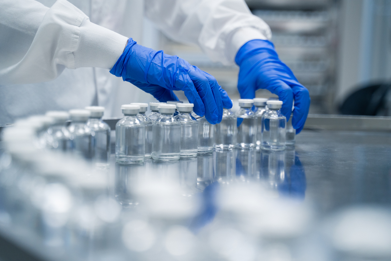 2173467915 Detail of hands working in pharmaceutical factory manufacturing sterile bottles